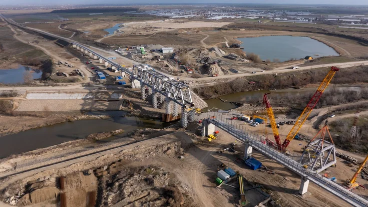 Brückenbaustelle über einen Fluss aus der Vogelperspektive mit gelb-rotem Kran