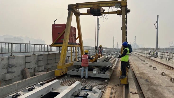 Construction workers install the slab track using a crane.