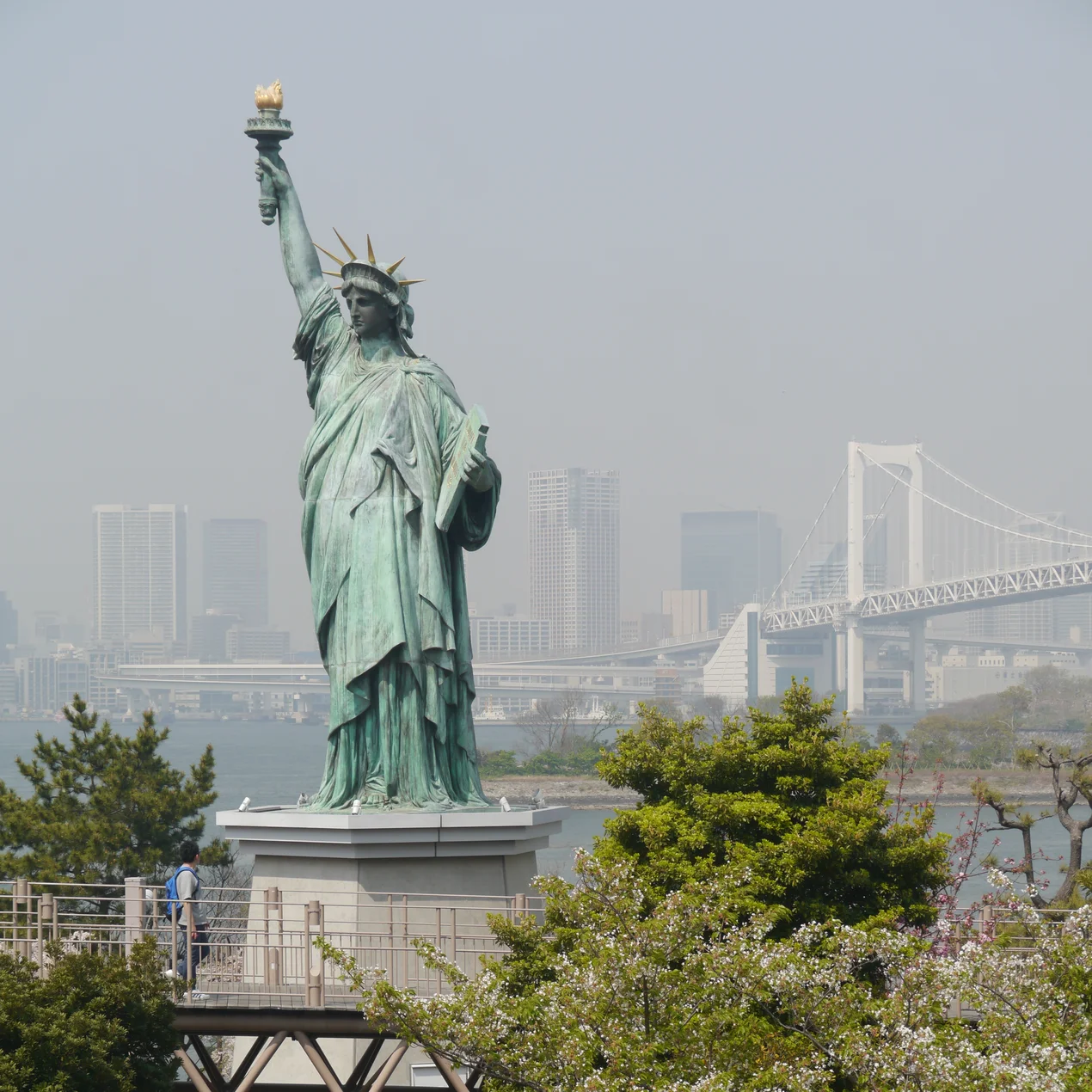 Statue of Liberty on a pedestal with a bridges in the background