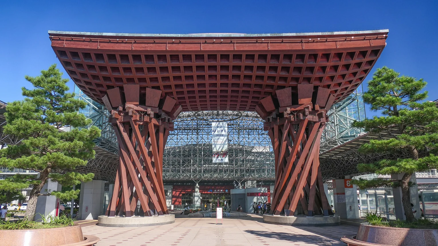 traditionell japanisches Tor, dahinter Bahnhof aus Stahl-Glas-Konstruktion