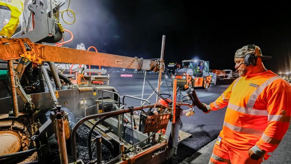 Bauarbeiter bei der Sanierung einer Rollbahn am Flughafen bei Nacht