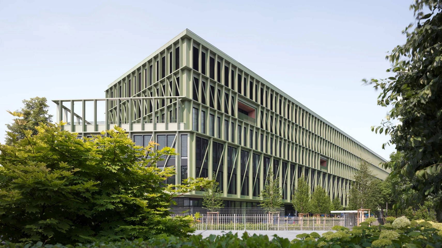 an elongated office block with a façade of glass and green aluminium