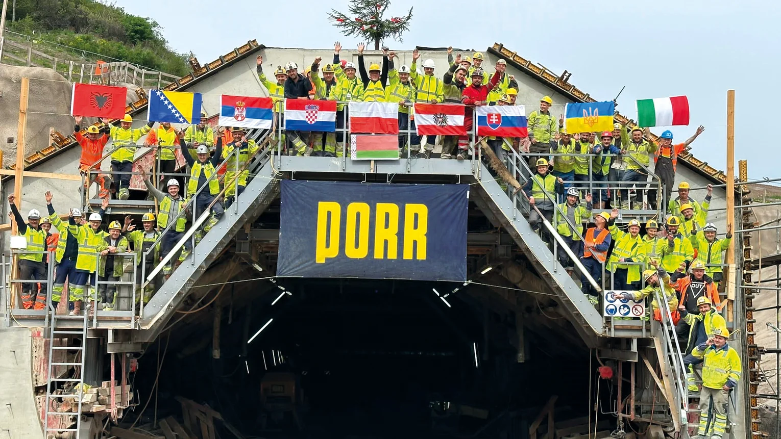 Gruppenfoto mit Bauarbeitern bei einem Tunnel mit PORR Transparent