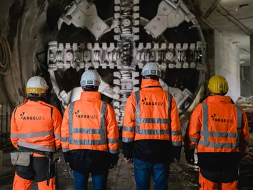 Vier Bauarbeiter vor einer Tunnelbohrmaschine
