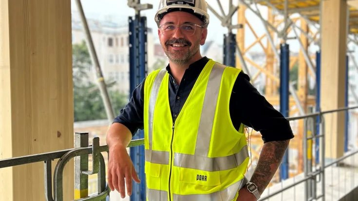 Mann mit Helm und gelber Warnweste auf der Baustelle