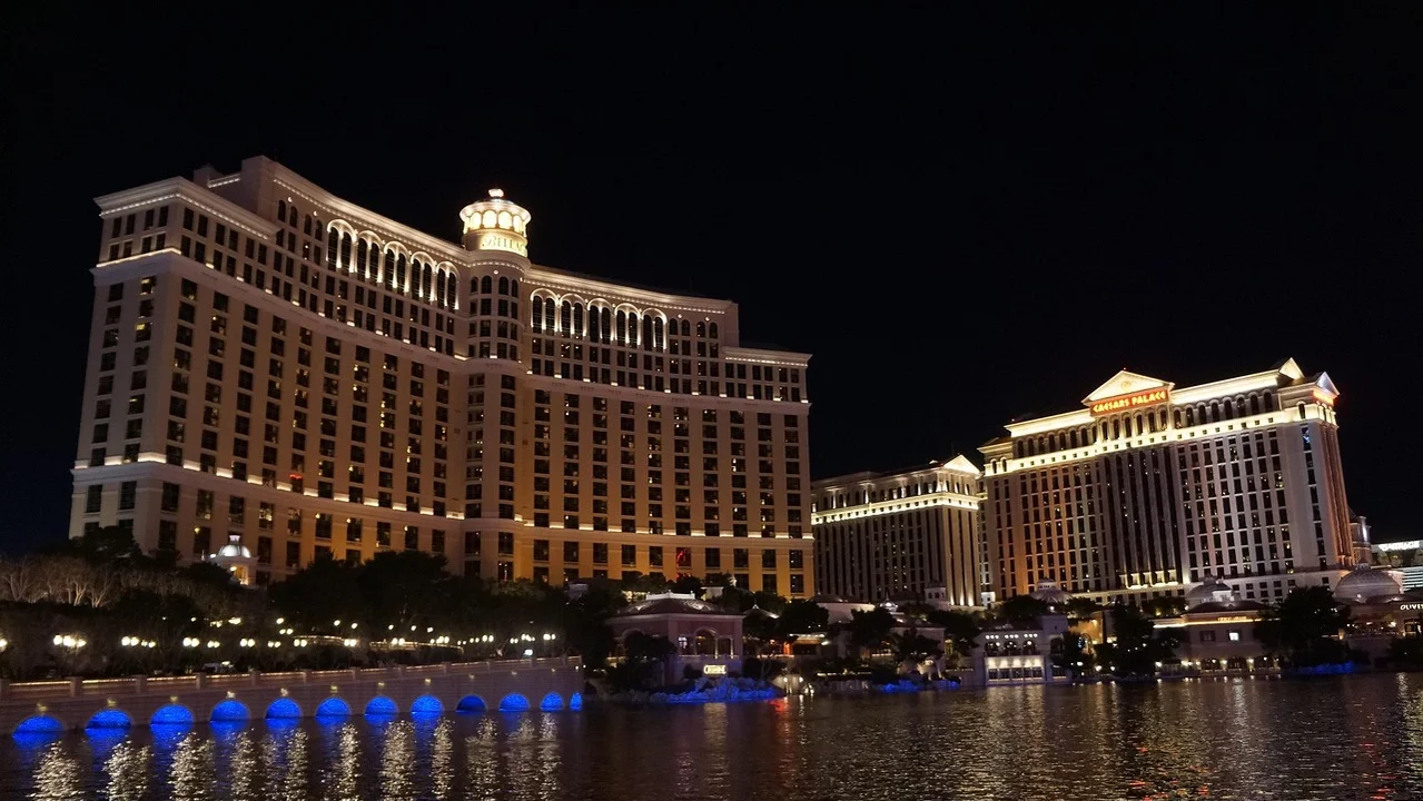 Großer beleuchteter Hotelkomplex bei Nacht, Wasser im Vordergrund